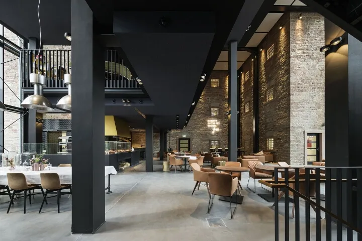 工業風餐廳室內,裸露磚牆、混凝土地板及金屬欄杆