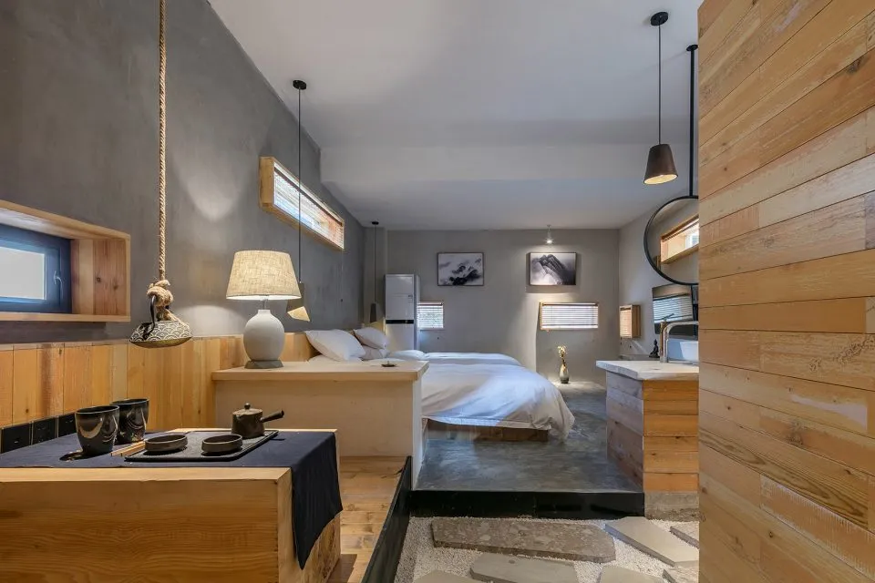 A minimalist bedroom featuring wooden and concrete elements, with a single bed, hanging lamps, and minimalist furnishings.