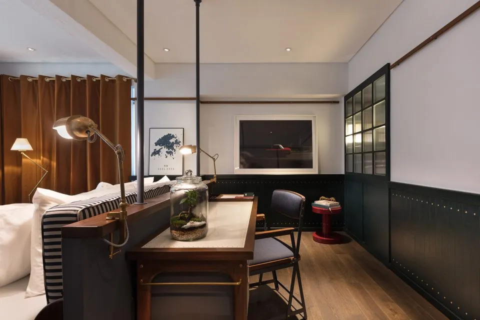 Modern home office space with a desk, chair, desk lamp, and framed picture, featuring wood and metal materials.