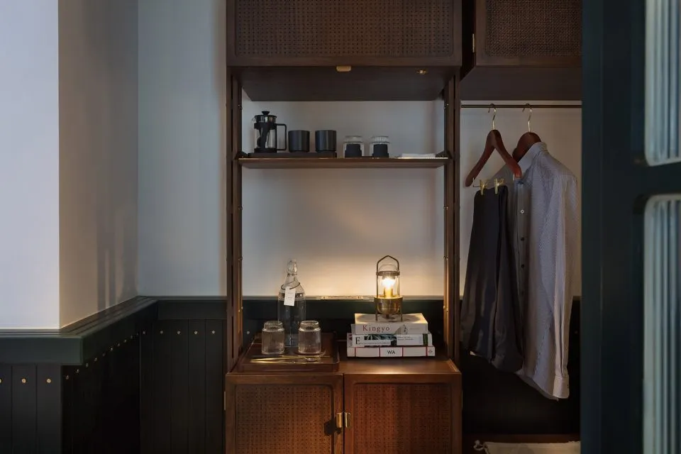 A modern wardrobe with dark wood shelves and clothing hanging inside.