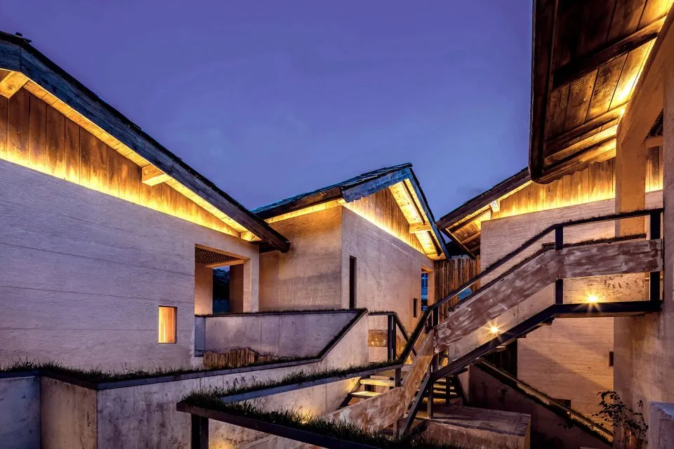 Modern wooden facade illuminated at night with warm lighting.