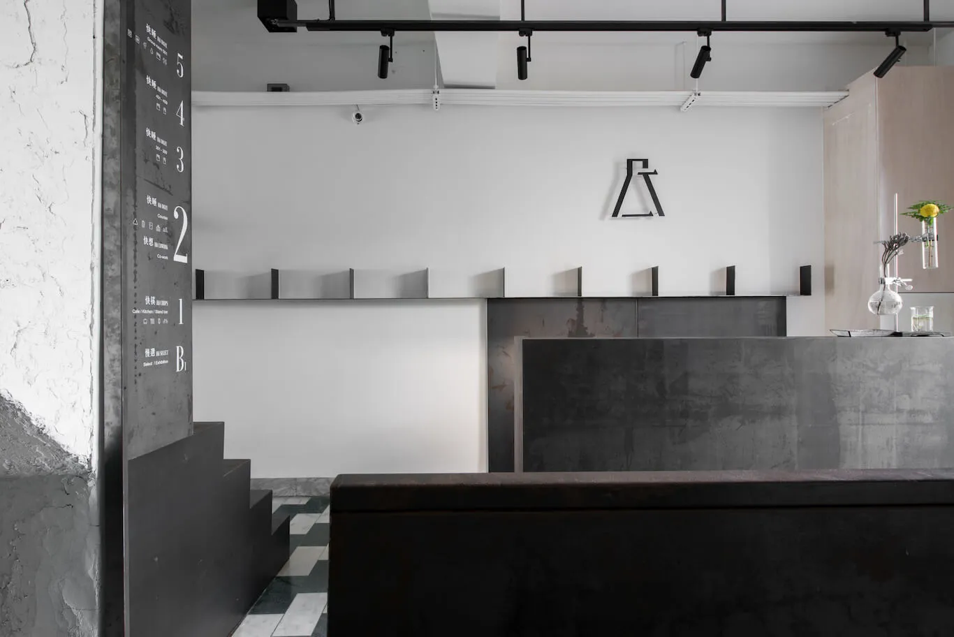 A minimalist industrial-style coffee shop with black and white decor, emphasizing the sleek metallic and concrete surfaces of