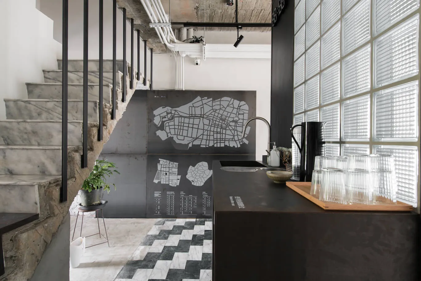 Industrial kitchen with concrete stairs, glass block wall, and concrete counter with black map.