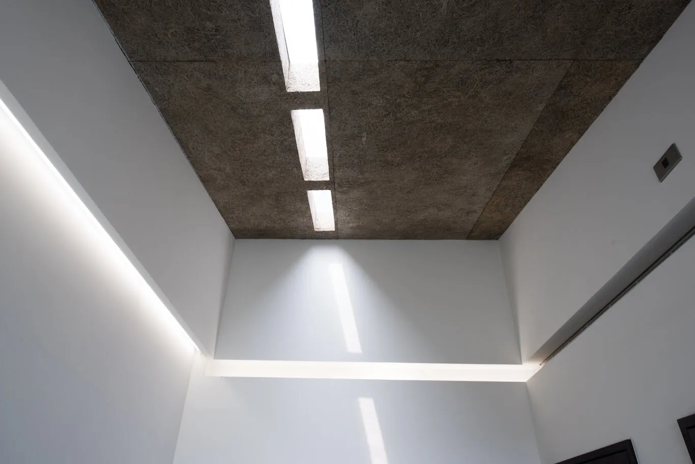 現代室內設計,展現紋理混凝土天花板板材與線性燈具。