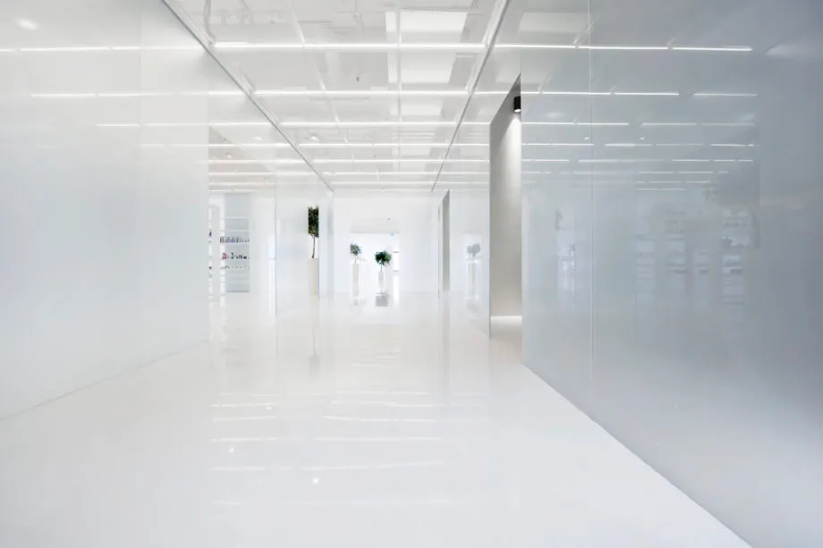 A sleek, minimalist office interior featuring white walls and a glass wall.