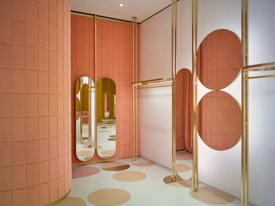 Modern retail shop with pink tiles and brass mirrors.