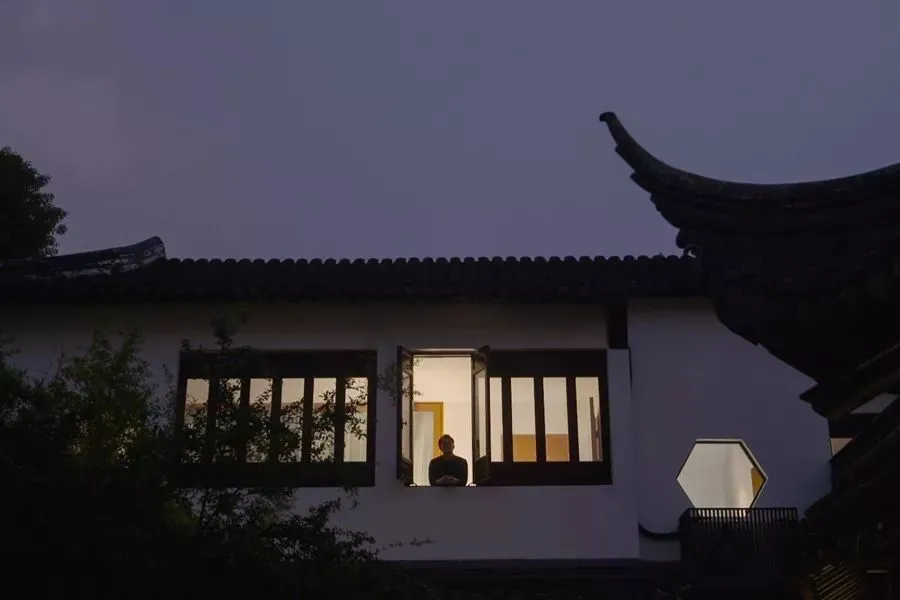 A residential exterior with white painted walls and terrazzo tile flooring during the evening.