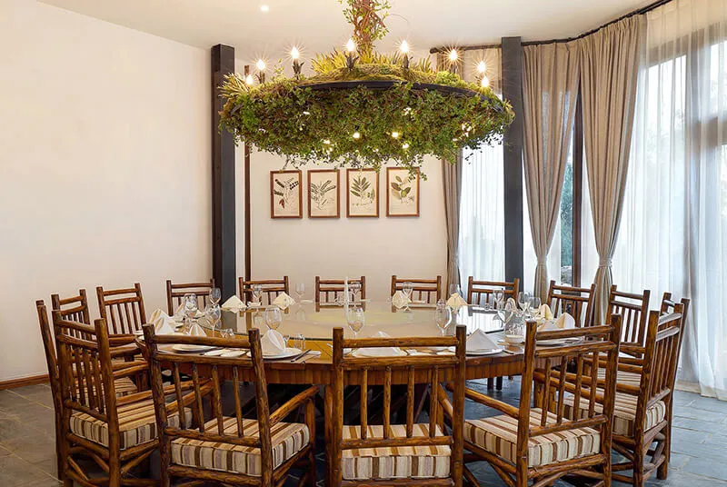 A round dining table made of bamboo surrounded by matching chairs in a restaurant dining room.