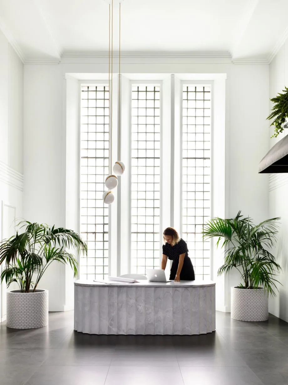 A minimalist office space featuring a marble table and potted plants.