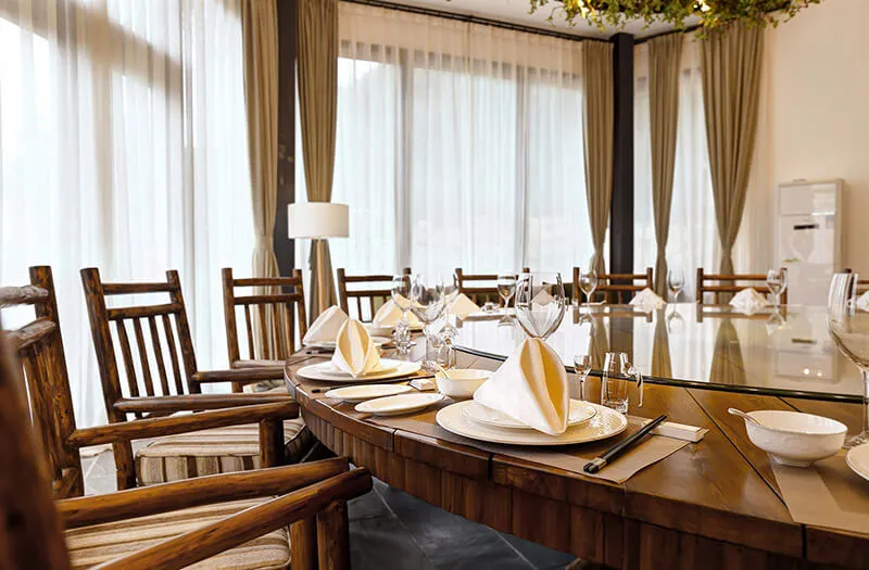 A modern restaurant dining area with a wooden table set for a meal.