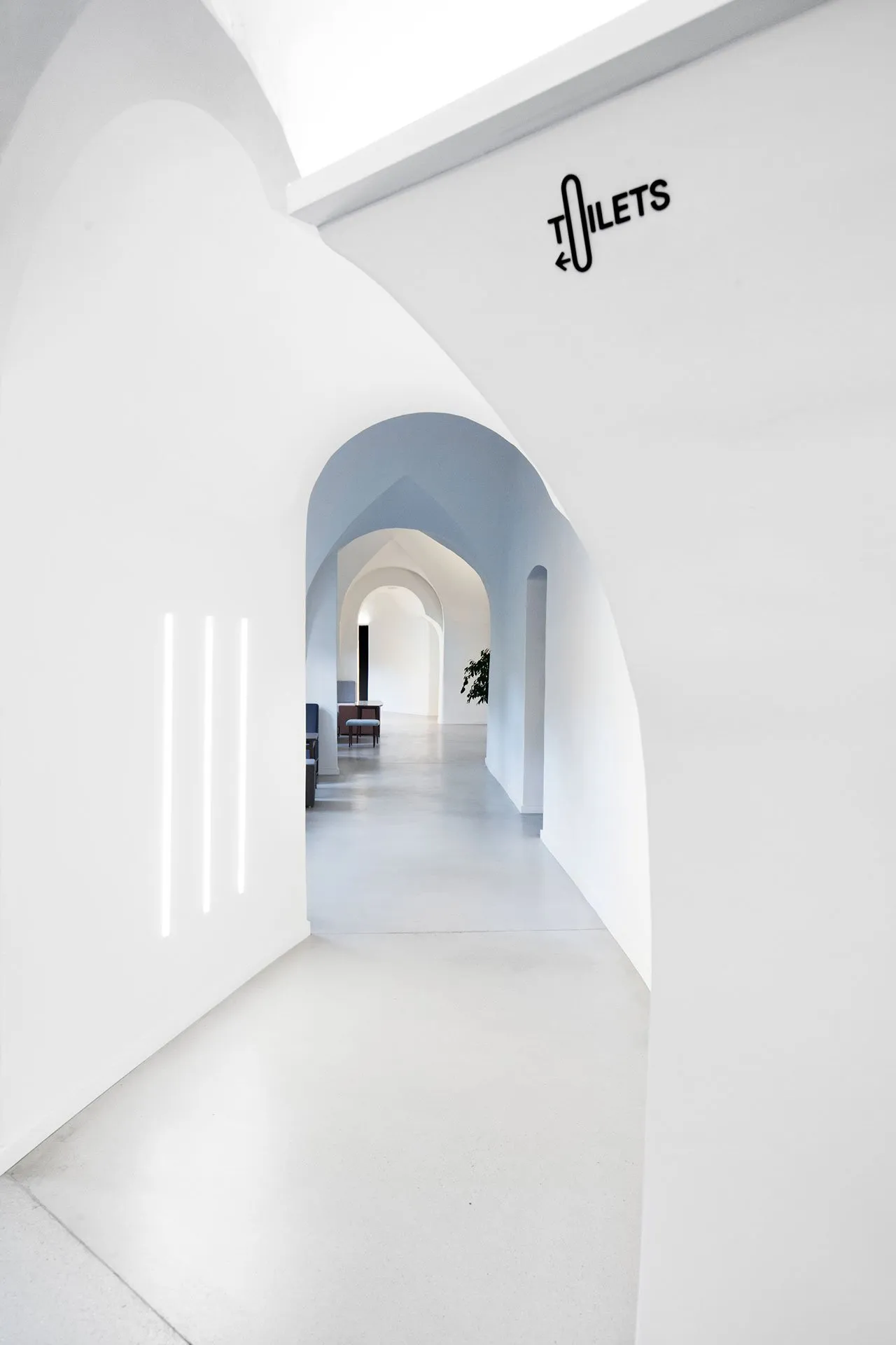 A minimalist office space with white walls and concrete surfaces.