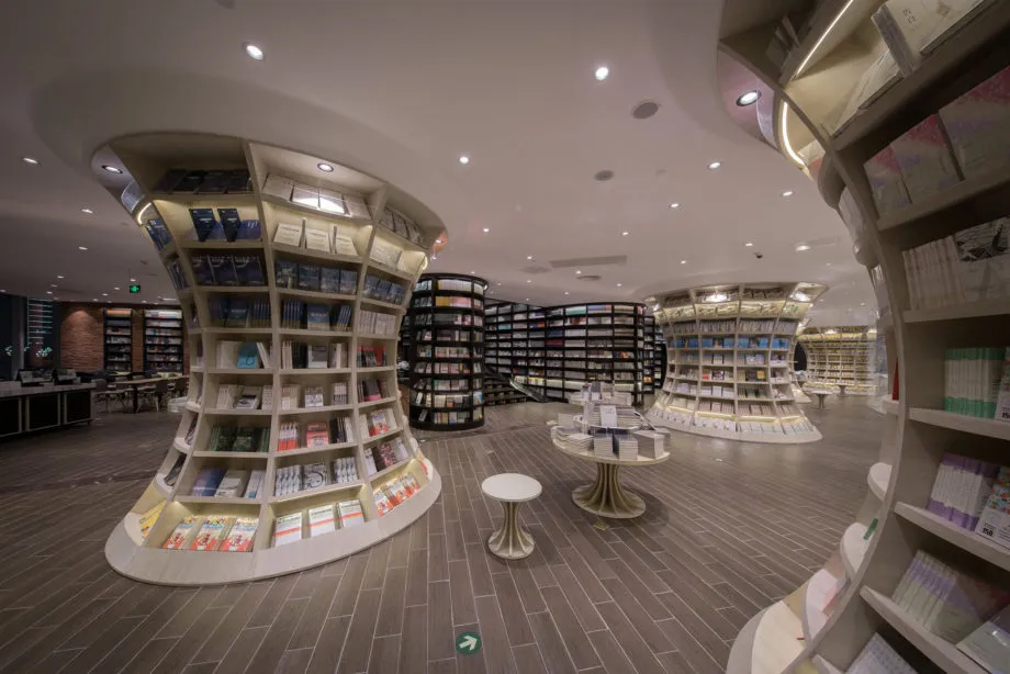 A spacious library interior featuring modern design elements such as wooden shelves, glass walls, and stylish lighting fixtur