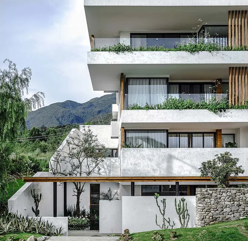 A modern residential building with multiple stories featuring concrete, glass, and wood materials.