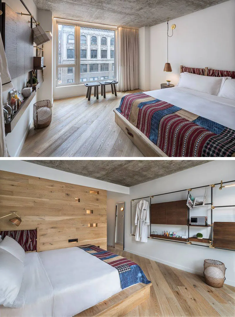 A modern hotel bedroom featuring concrete walls, wood flooring, a large bed with colorful bedding, and a minimalist design.