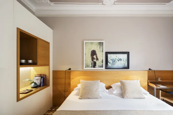 A minimalist bedroom featuring a wooden headboard and paneled walls.