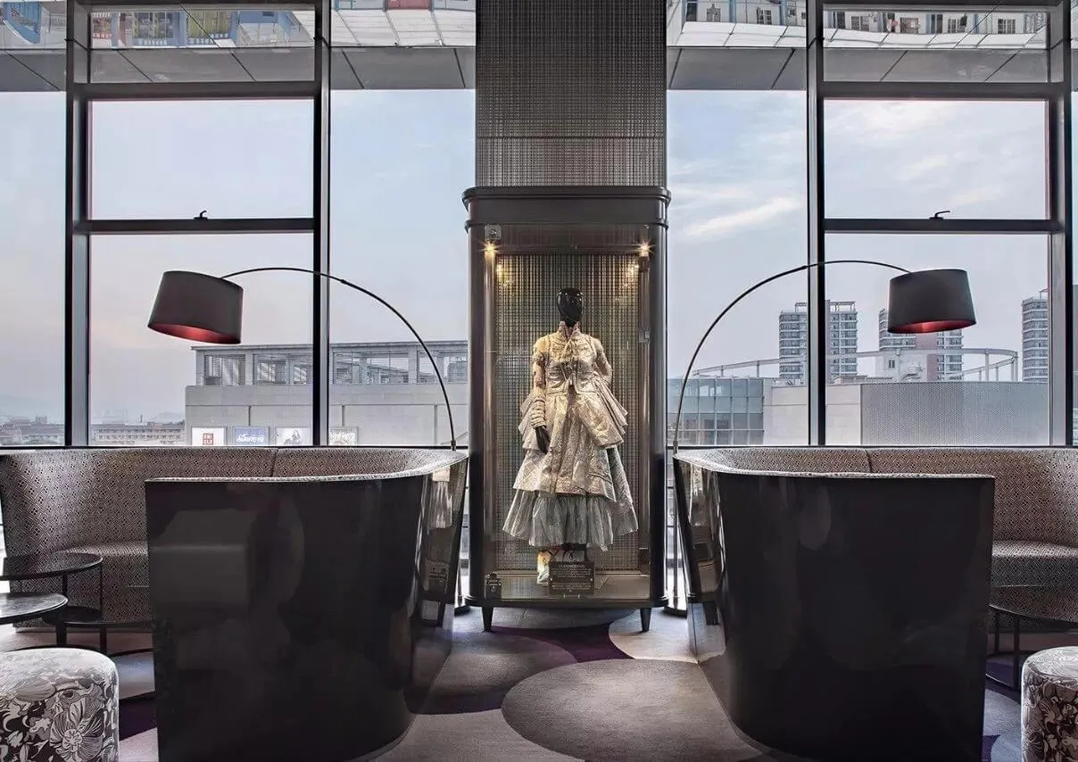 Modern hotel lobby featuring glass enclosed display and stylish seating with floor-to-ceiling windows.
