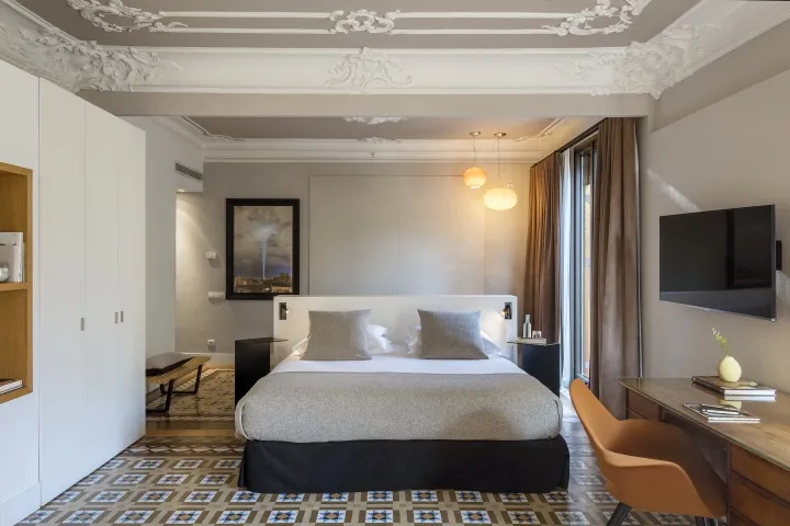 A modern hotel room featuring a king-sized bed, white and gray color scheme, and a large window.