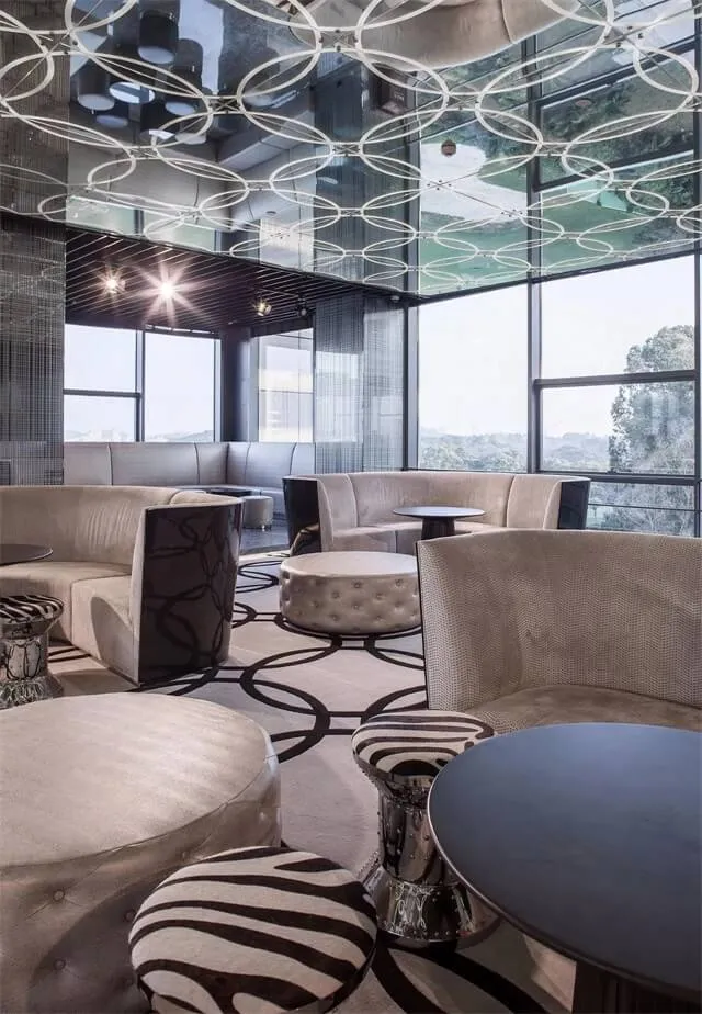Modern lounge interior featuring fabric seating, glass tables, and metal accents.