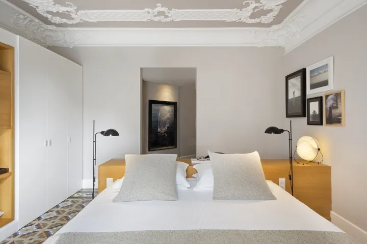 A minimalist bedroom with a large bed, white walls, and wooden headboard and nightstands.