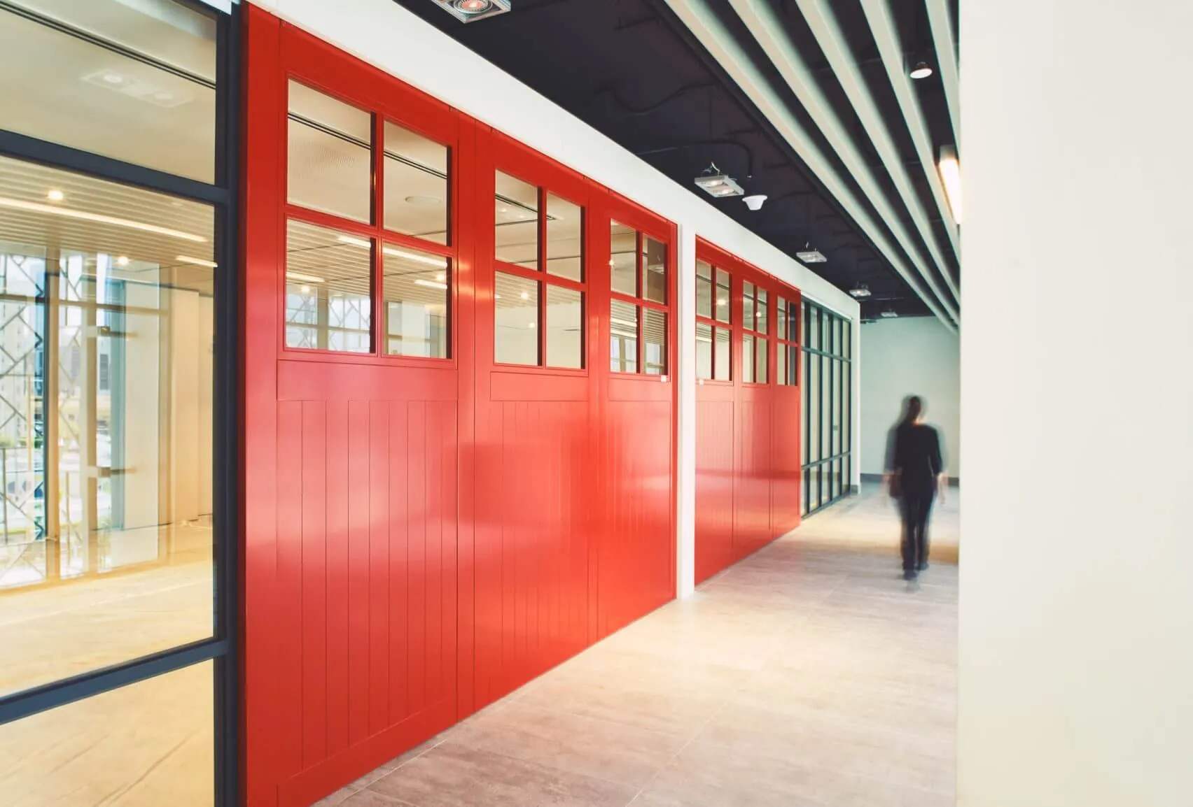 A modern office corridor featuring red glass panels and white walls.