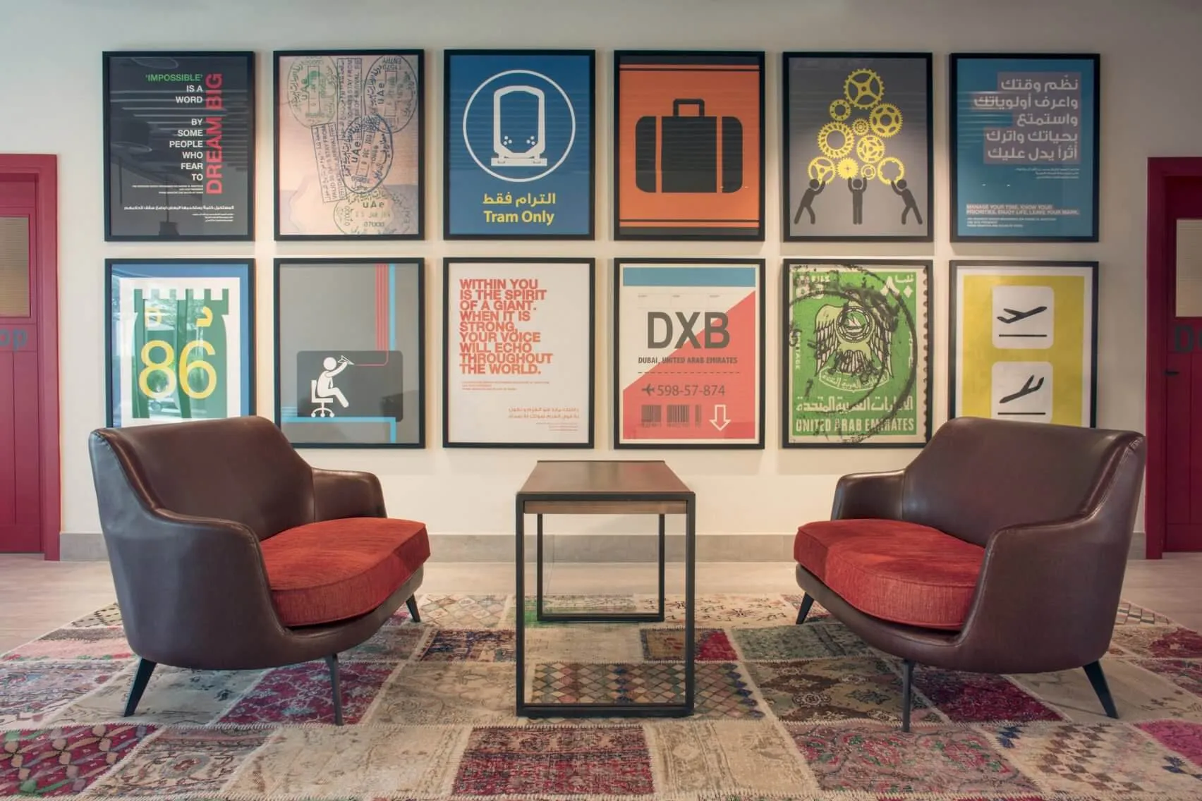 Modern office space with two brown armchairs, a wooden table, and colorful posters on the wall.
