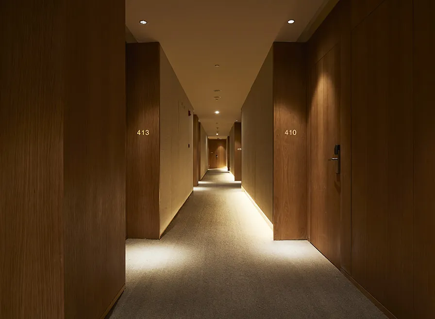 A modern hotel corridor with wood paneling.