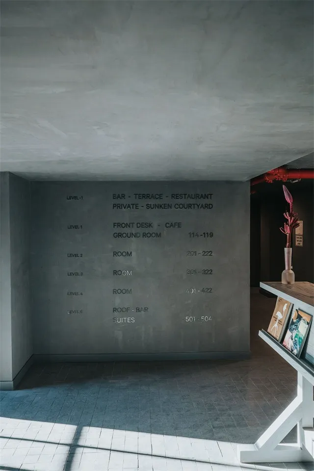 Interior view of an industrial-style room with concrete floors and walls, listing room numbers on the wall.