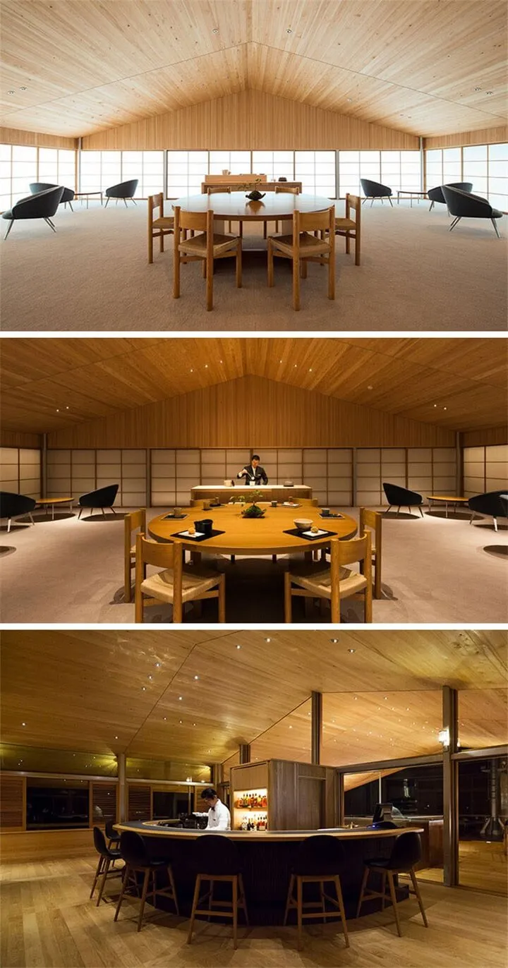 Modern restaurant interior with wooden tables and chairs, large windows, and a high wooden ceiling.