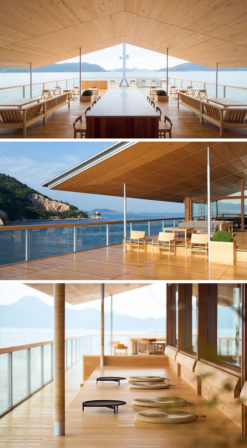 A modern residential interior featuring a wooden ceiling, large windows overlooking the water, and a communal dining area wit