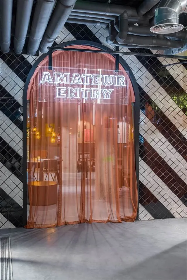 A modern entryway featuring a glass curtain and an illuminated sign reading 'Amateur Entry'.