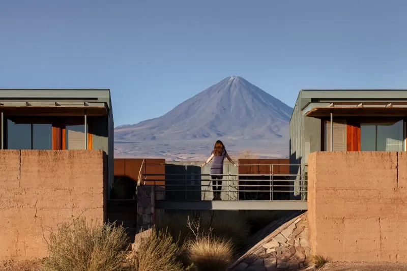 Person standing on a concrete balcony overlooking a mountainous landscape.