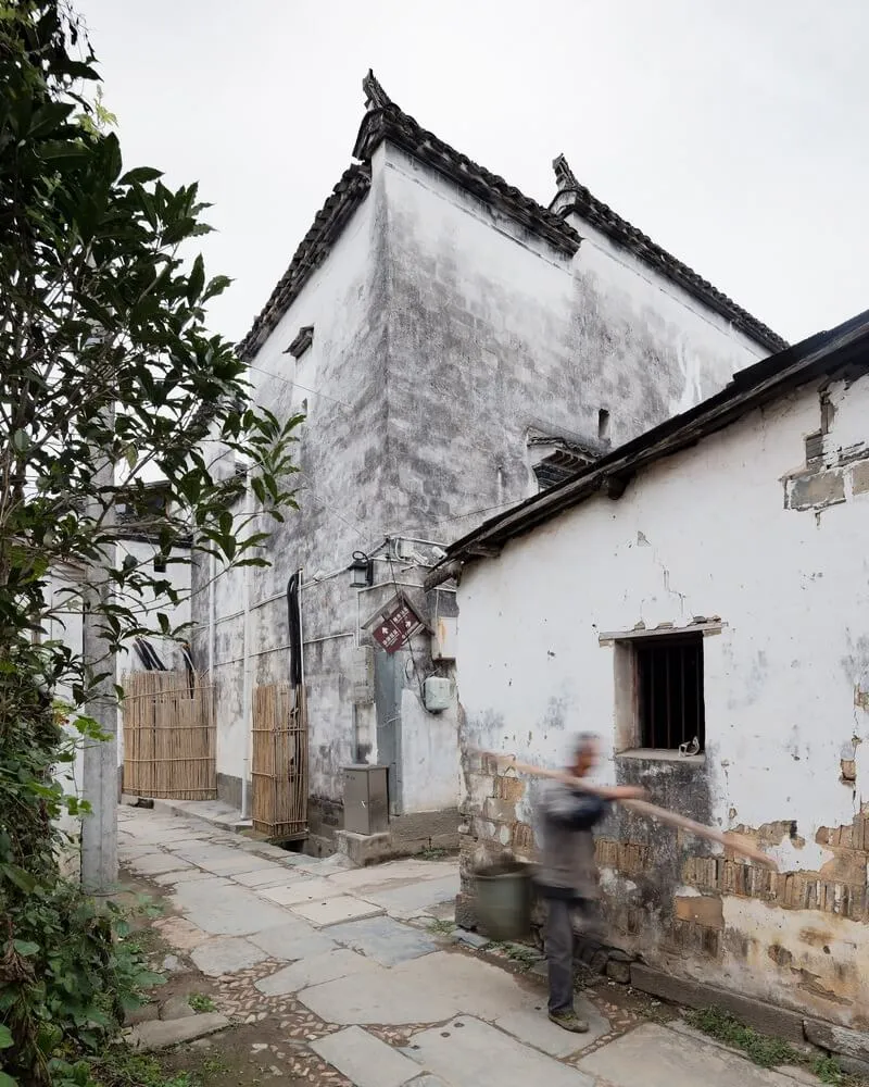 一條狹窄的城市街道，兩旁是混凝土與木質建造的古建築。