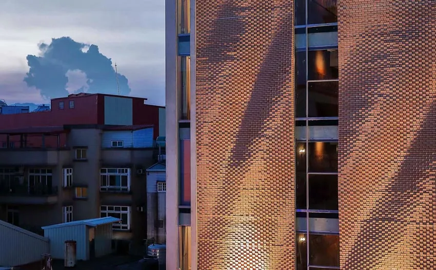 A brick building with a sunset casting a warm glow on its facade.