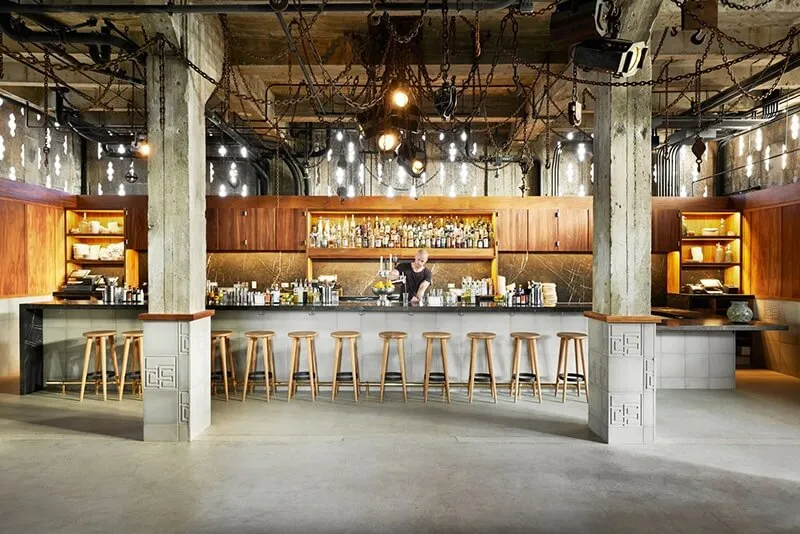 Industrial-style bar with concrete, wood, and metal elements.