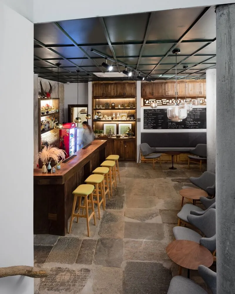 Industrial-style cafe bar with wooden seating, stone flooring, and metal accents