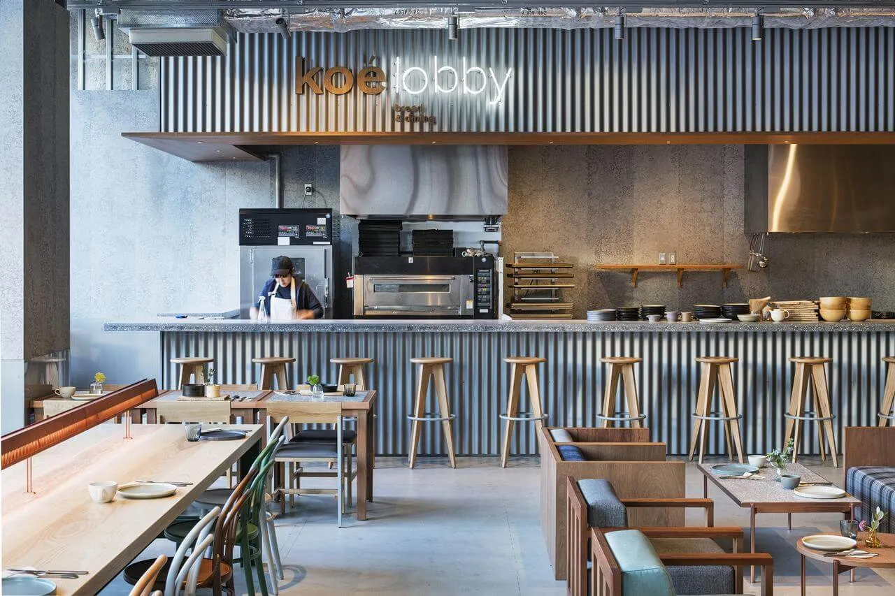 Modern industrial cafe with metallic walls, wooden stools, and concrete flooring.
