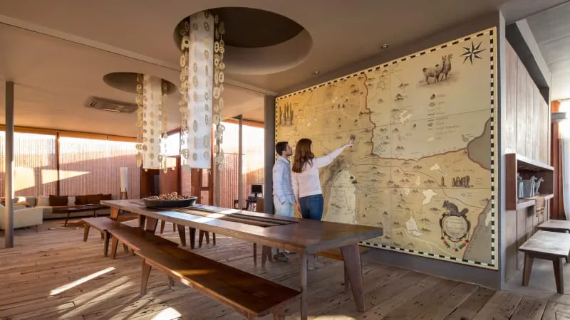 Two people studying an intricate wall map in a warm, industrial-style restaurant interior