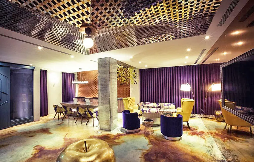 A modern living room with a concrete floor, purple curtains, and a metal ceiling.