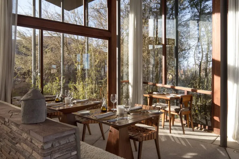 Modern restaurant interior featuring wooden furniture and glass windows.