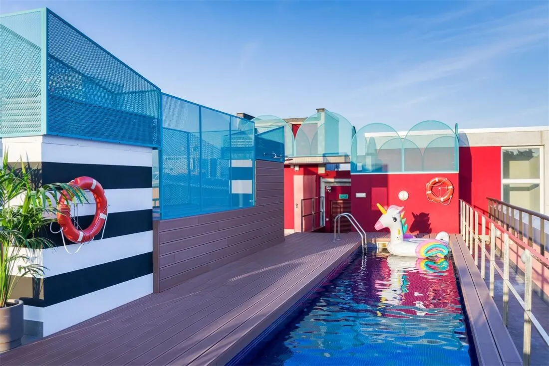 Modern rooftop pool with blue and red accents and a unicorn-shaped float