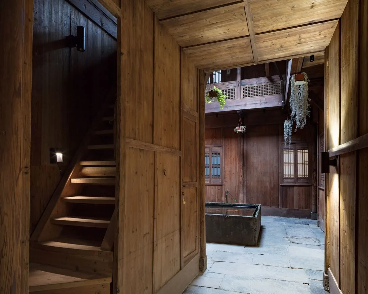 Traditional wooden living space with stairs and potted plants, featuring brown wooden walls and floors and white potted plant