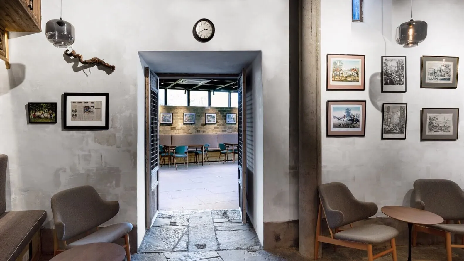 Concrete wall and floor of a cafe interior with framed artwork on the walls.