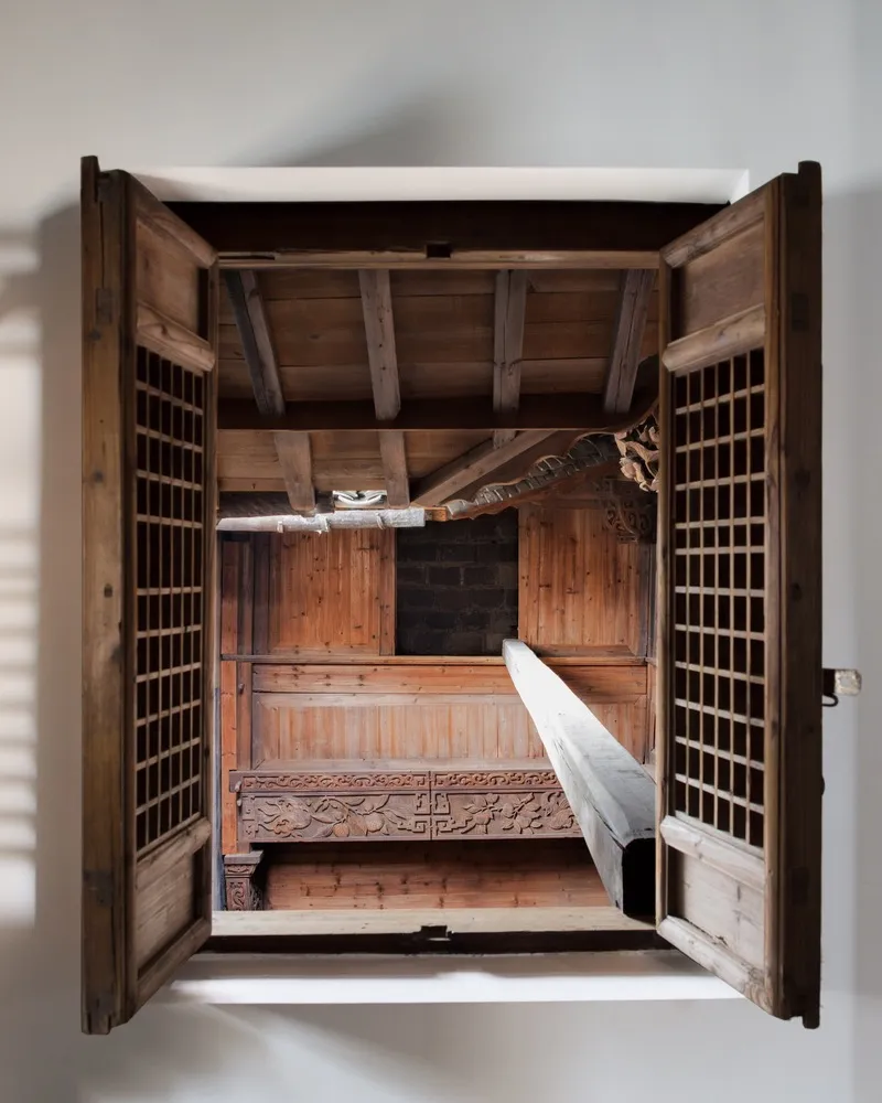 View of a traditional Japanese teahouse interior with wooden walls and ceiling beams.