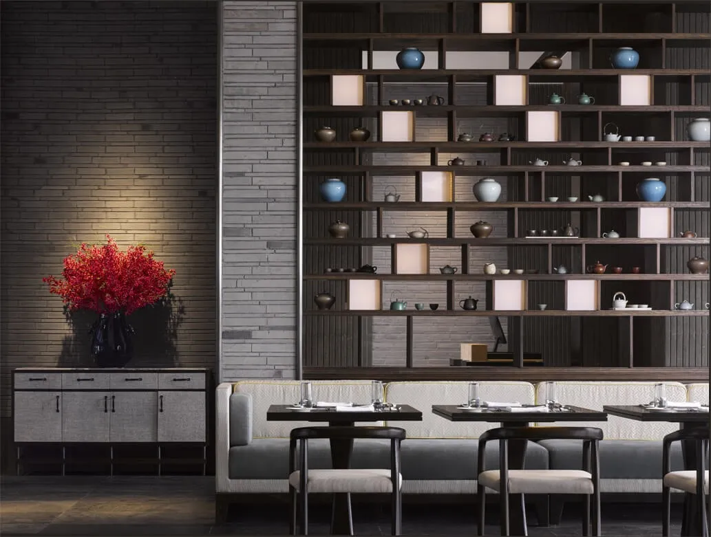 A modern restaurant interior with a long wooden bench, white cushions, and a large wooden bookshelf filled with tea sets