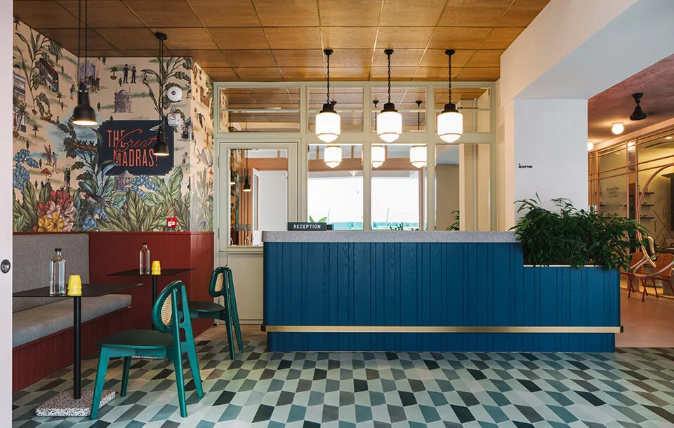 A modern coffee shop with a blue wooden counter, industrial-style decor, and a patterned floor.