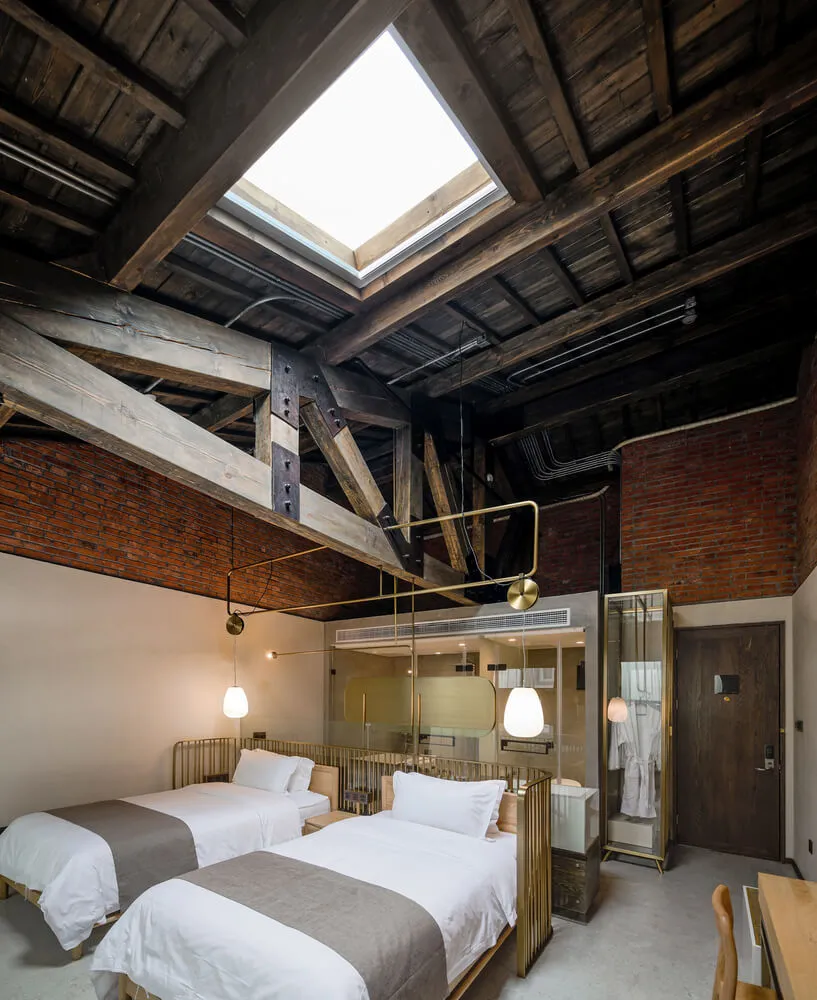 An industrial-style hotel room featuring brick walls and metallic furnishings.