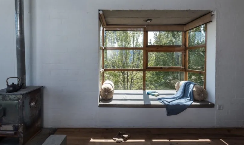 Industrial-style interior with wooden furniture, window seat, and natural light.