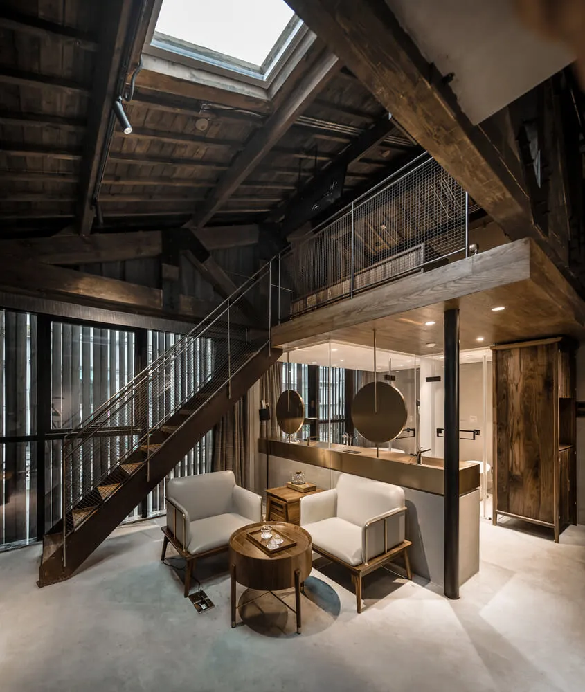 An industrial loft featuring white furniture and a moneybox, with wooden beams and a skylight.