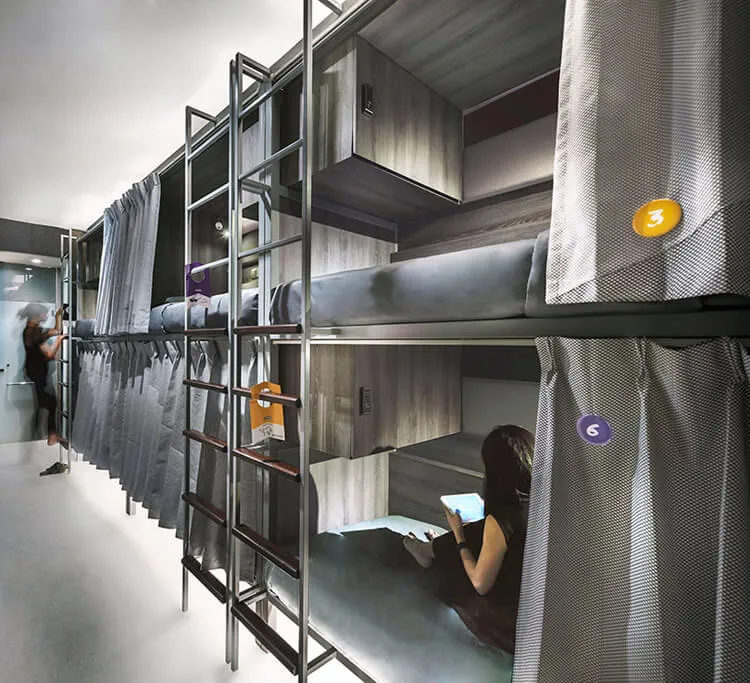 A metal bunk bed system with industrial design featuring wooden bunk beds and grey fabric curtains.