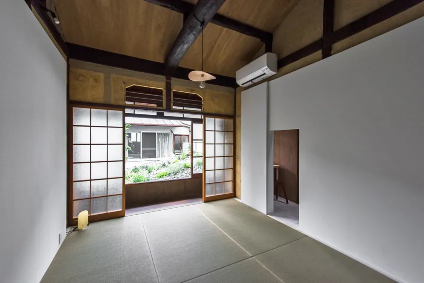 A minimalist residential interior featuring wooden walls, paper floors, and a paper air conditioning unit.
